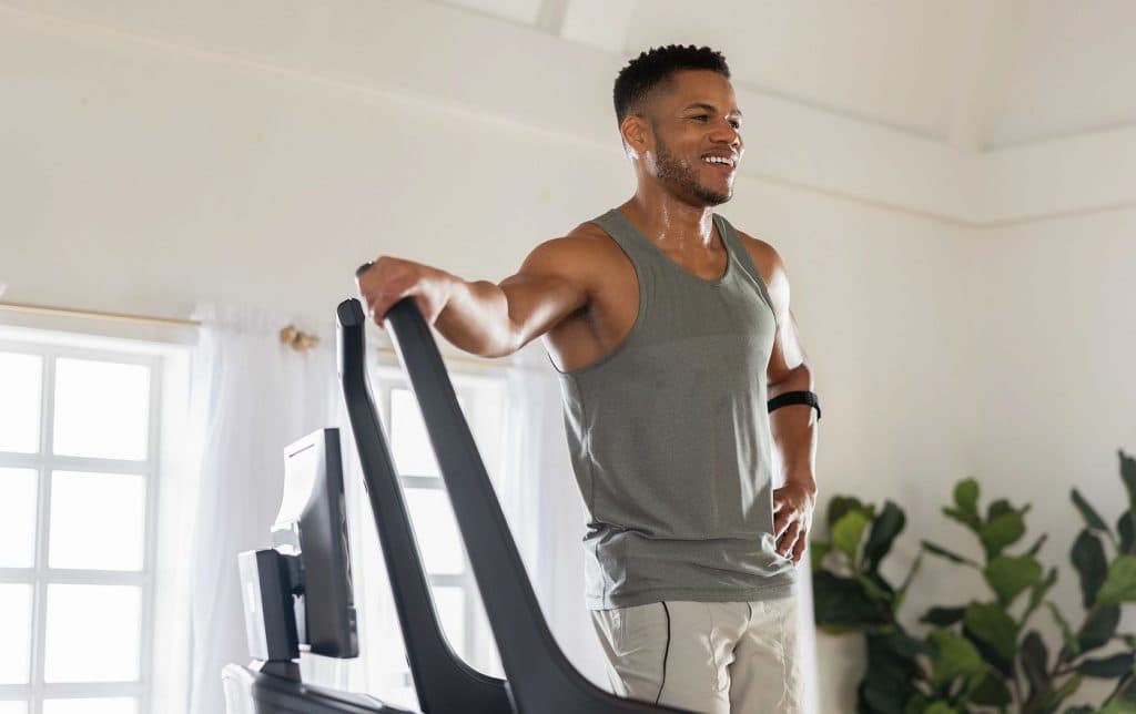 Individual walking on a NordicTrack treadmill in a bright home environment, highlighting aerobic exercise for heart health and endurance.