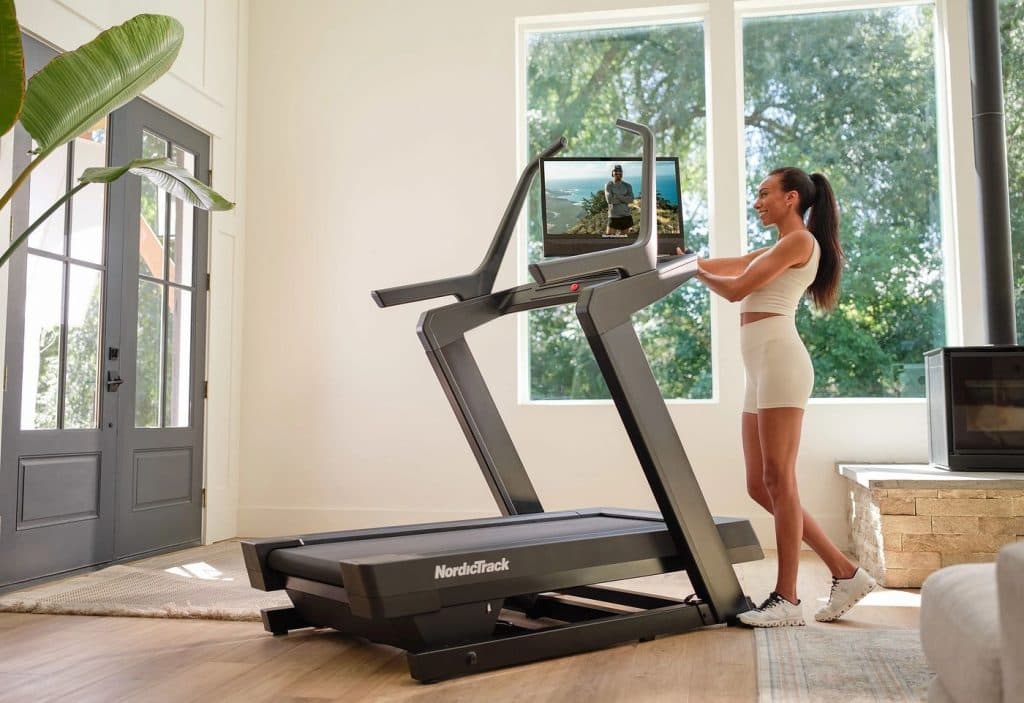 A user walking at incline on a NordicTrack treadmill while following a guided iFIT workout, illustrating structured and adaptable home cardio training.